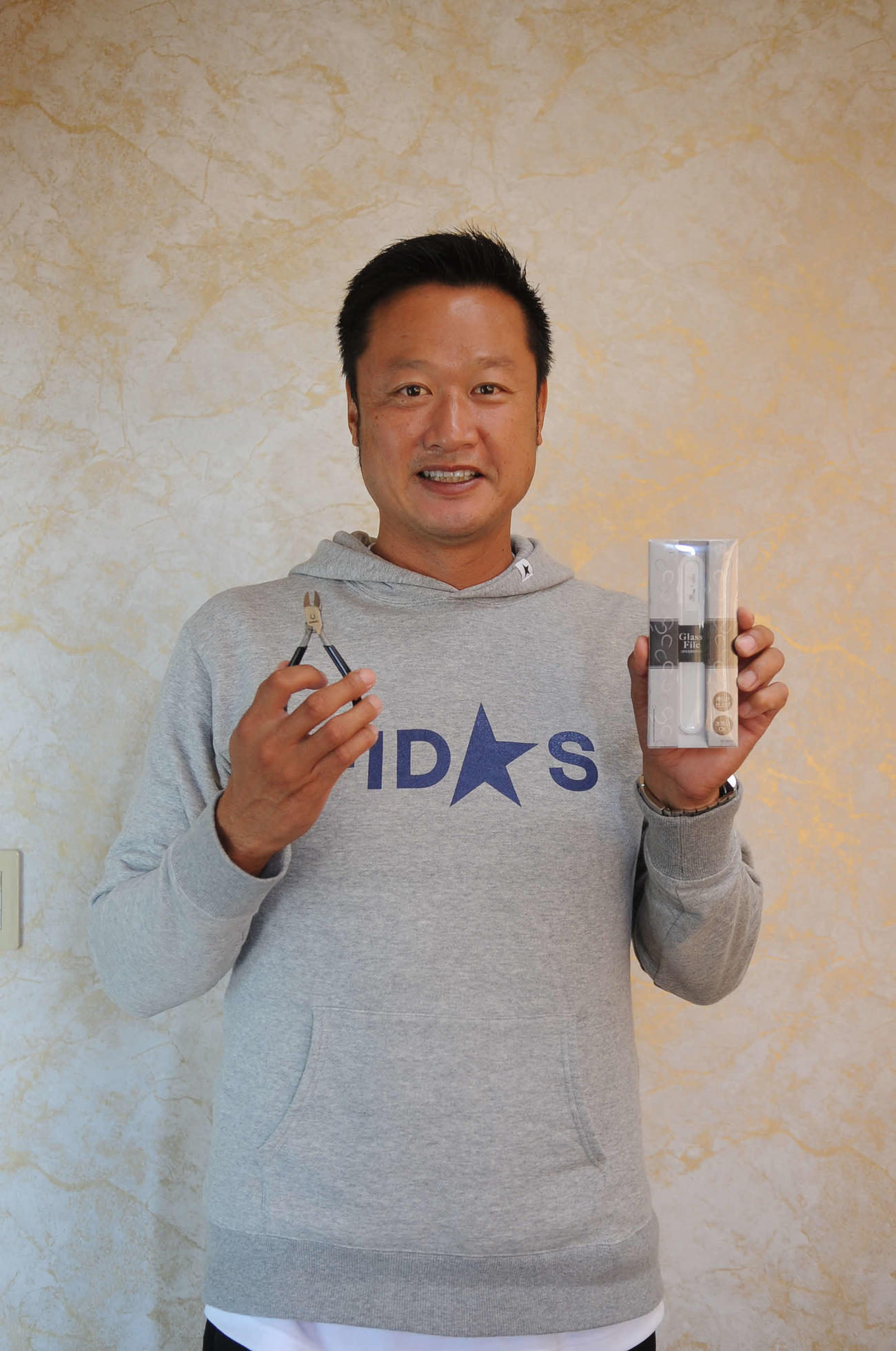 商品を手に爪のケアの大切さを話すマック鈴木氏