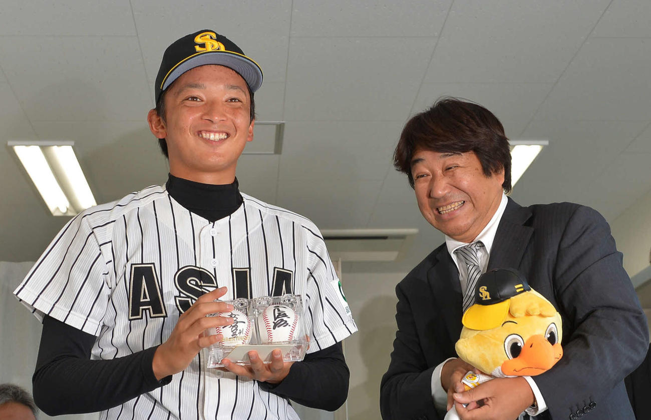 ソフトバンク1位の亜大・東浜（中央）は指名あいさつに訪れたソフトバンク永山スカウト部長（右）から帽子と王会長、秋山監督のサインボールをプレゼントされ笑顔を見せる。（2012年10月26日撮影）