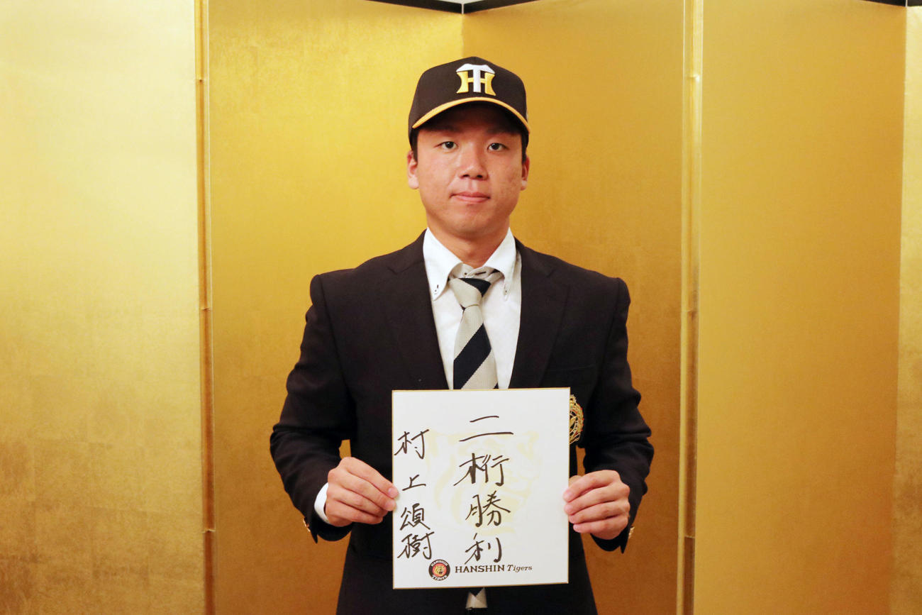 阪神と仮契約を結んだ村上頌樹は目標を書いた色紙を手に引き締まった表情を見せる（球団提供）