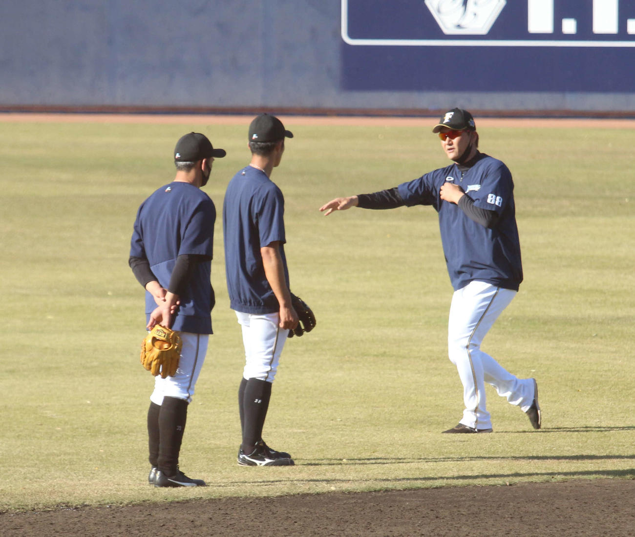 鎌ケ谷での秋季練習で日本ハム石井の特守中にアドバイスを送る金子野手総合コーチ（右）と飯山内野守備コーチ（左）（撮影・木下大輔）