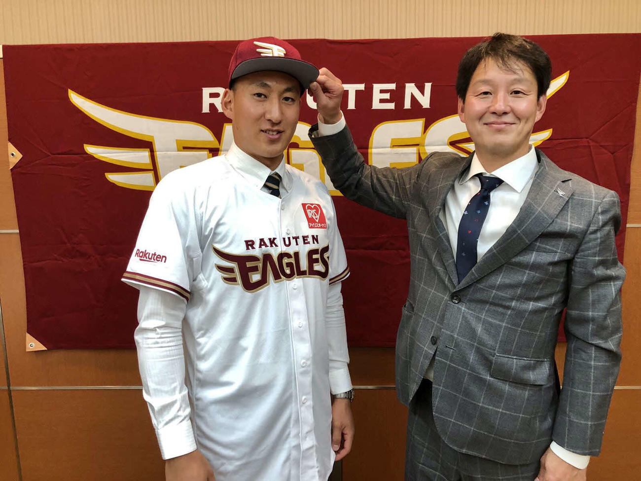 入団交渉を終え、部坂スカウト（右）に帽子をかぶせてもらう楽天ドラフト2位の法大・高田（左）（球団提供）