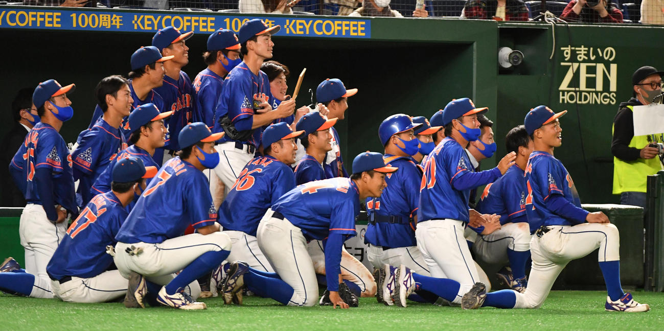 日本製紙石巻対西部ガス　都市対抗初勝利しインタビューを受ける西部ガス・香田監督を見つめるナイン（撮影・柴田隆二）