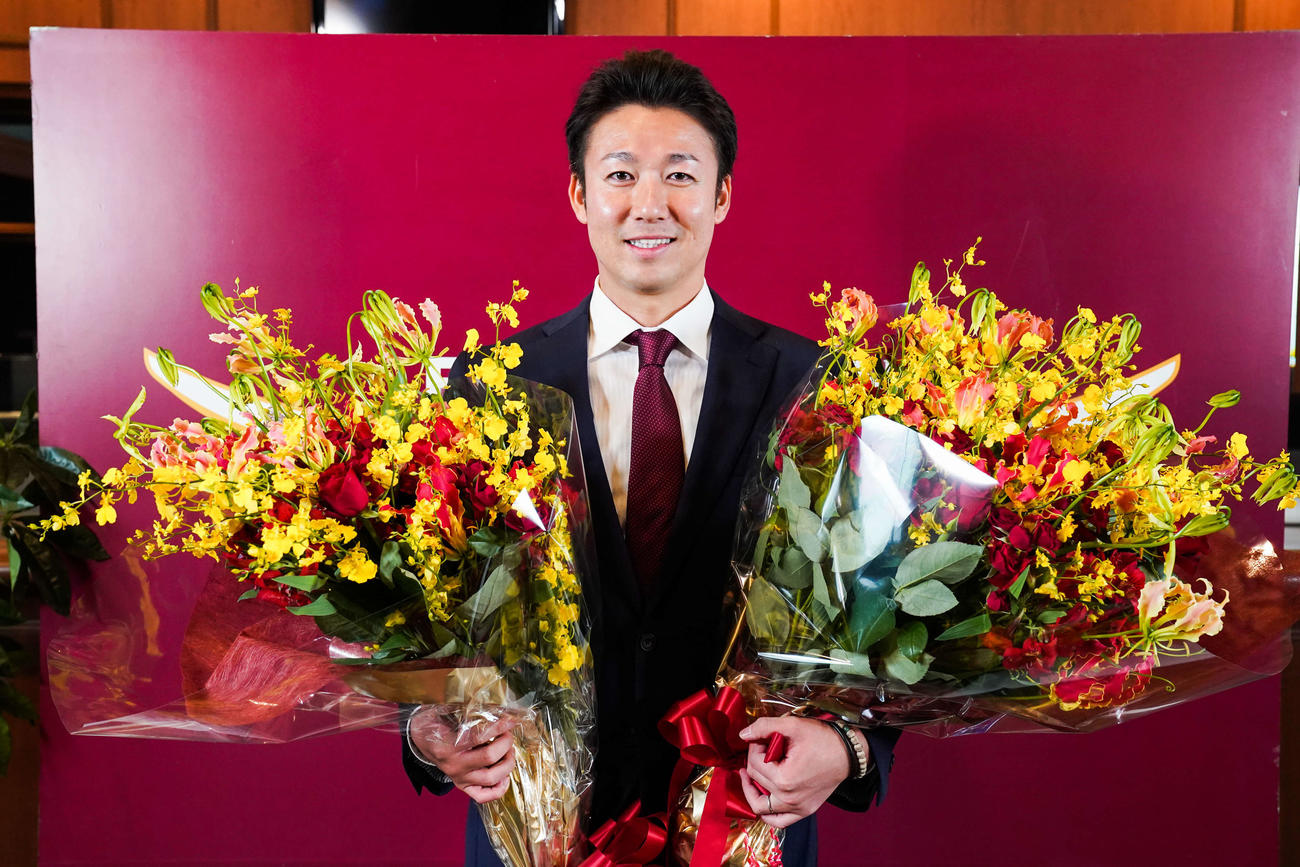 引退会見を終え、花束を抱えながら笑顔を見せる楽天青山（球団提供）
