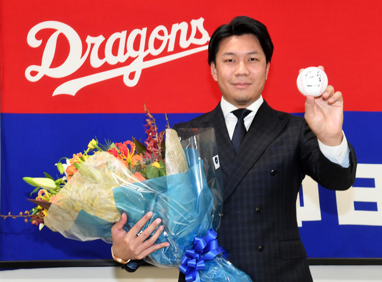 23日、沢村賞としたためたボールと花束を手に喜びの表情を見せる大野雄（撮影・前岡正明）