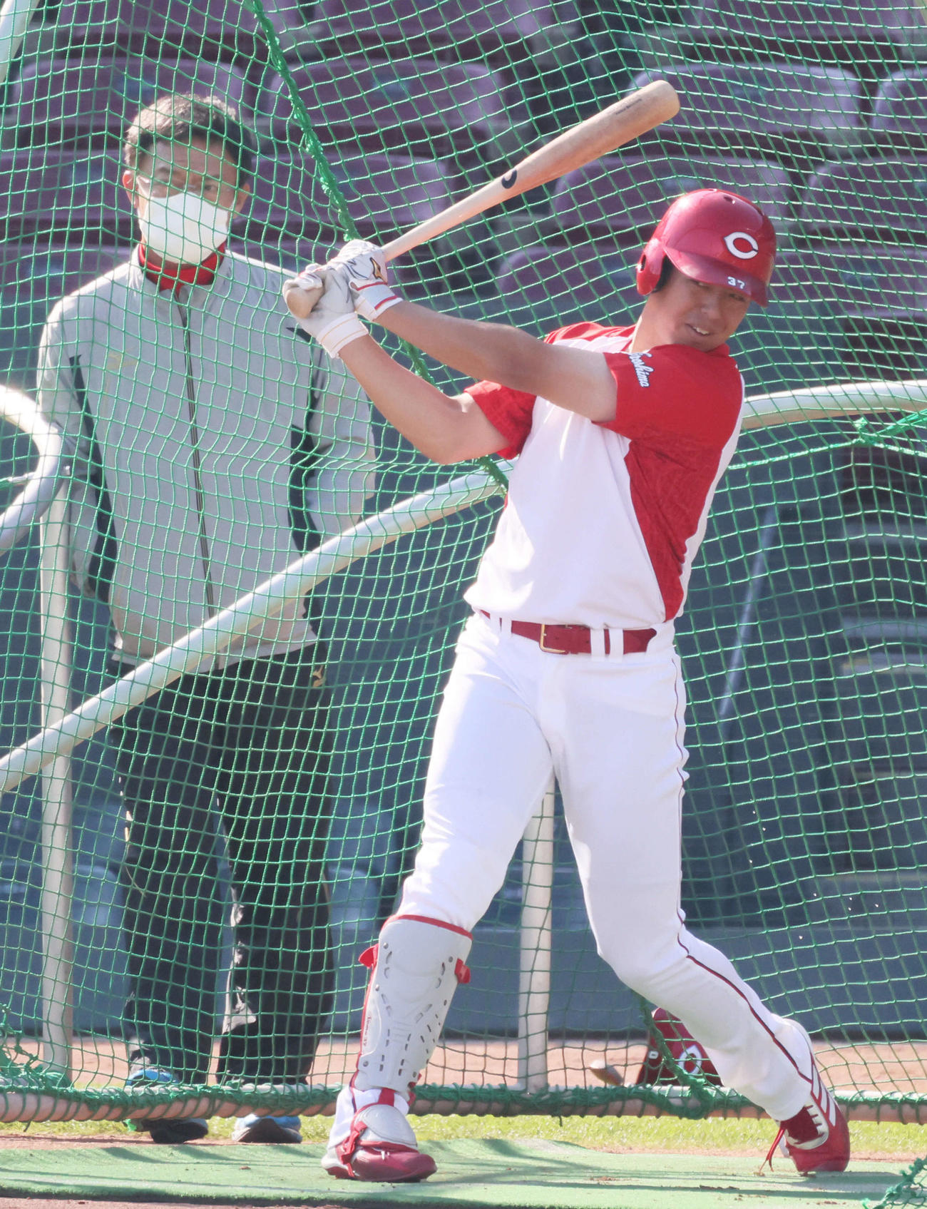 河田ヘッドコーチ（左）が見守る前で打撃練習を行う広島野間
