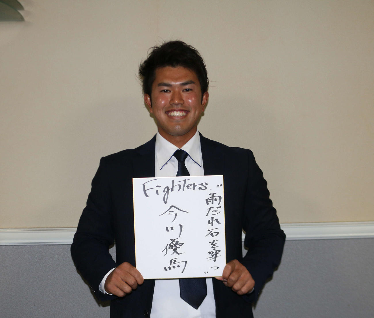 座右の銘「雨だれ石を穿つ」を書いた色紙を手に笑顔を見せる今川（撮影・田中彩友美）