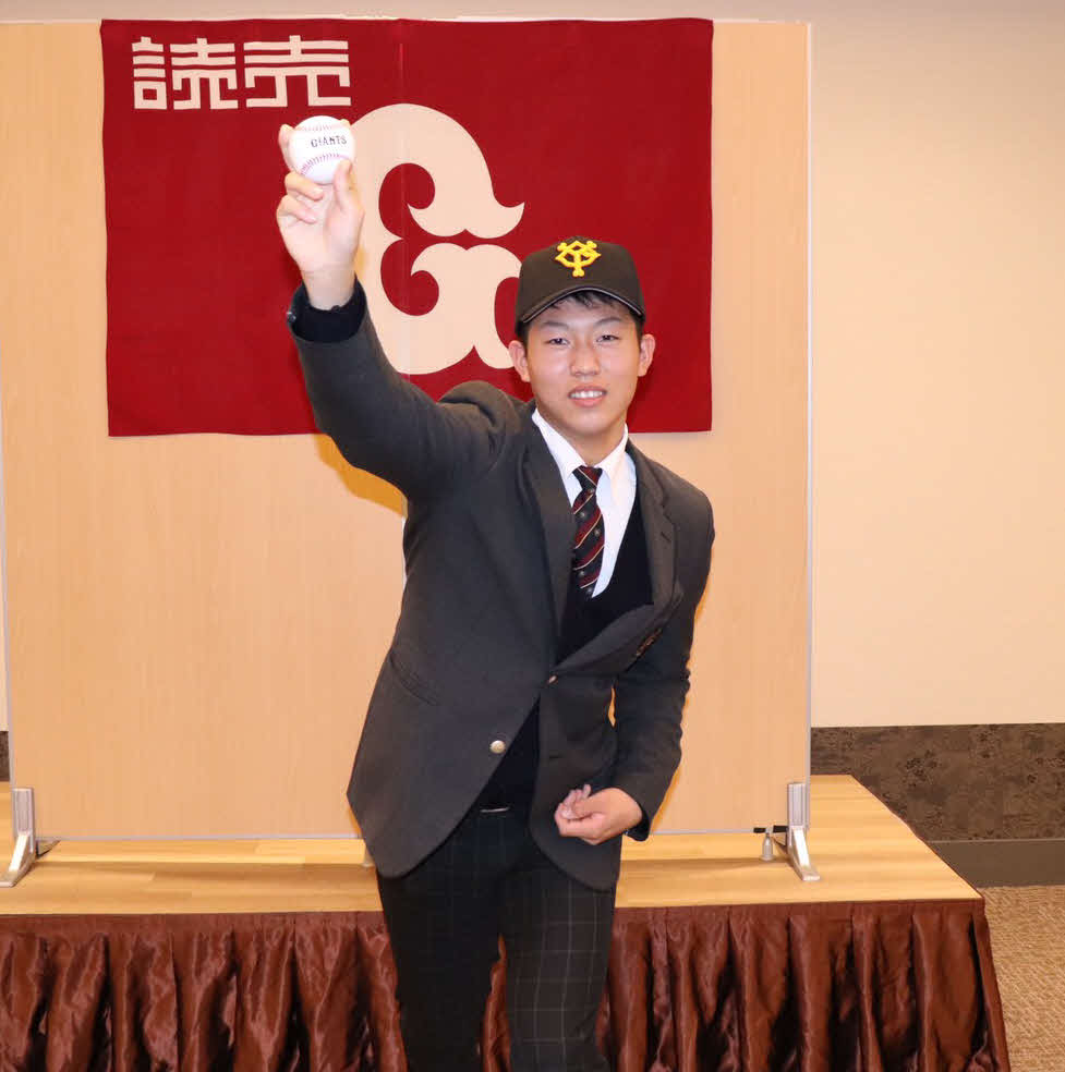 仮契約を結び、球団旗の前で投球フォームを見せる巨人育成3位敦賀気比・笠島（撮影・久永壮真）