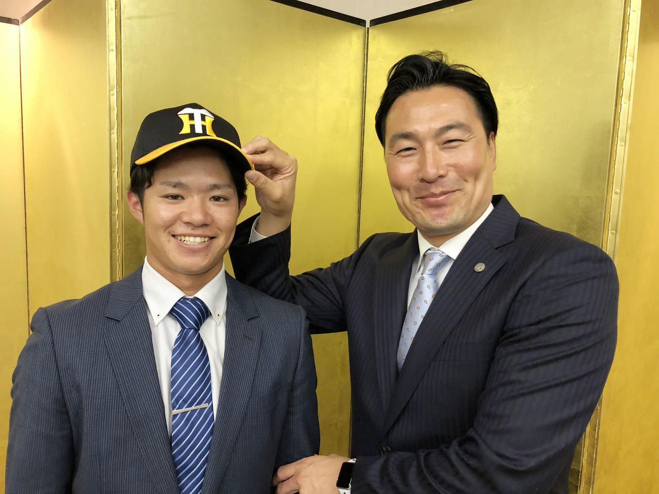 阪神と仮契約を結んだ中野（左）は筒井スカウトから帽子をかぶせてもらう（球団提供）