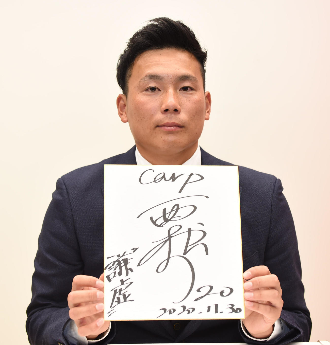 広島と仮契約を済ませたトヨタ自動車・栗林良吏は、色紙に背番号「20」と「謙虚」を書き込む（撮影・森本幸一）