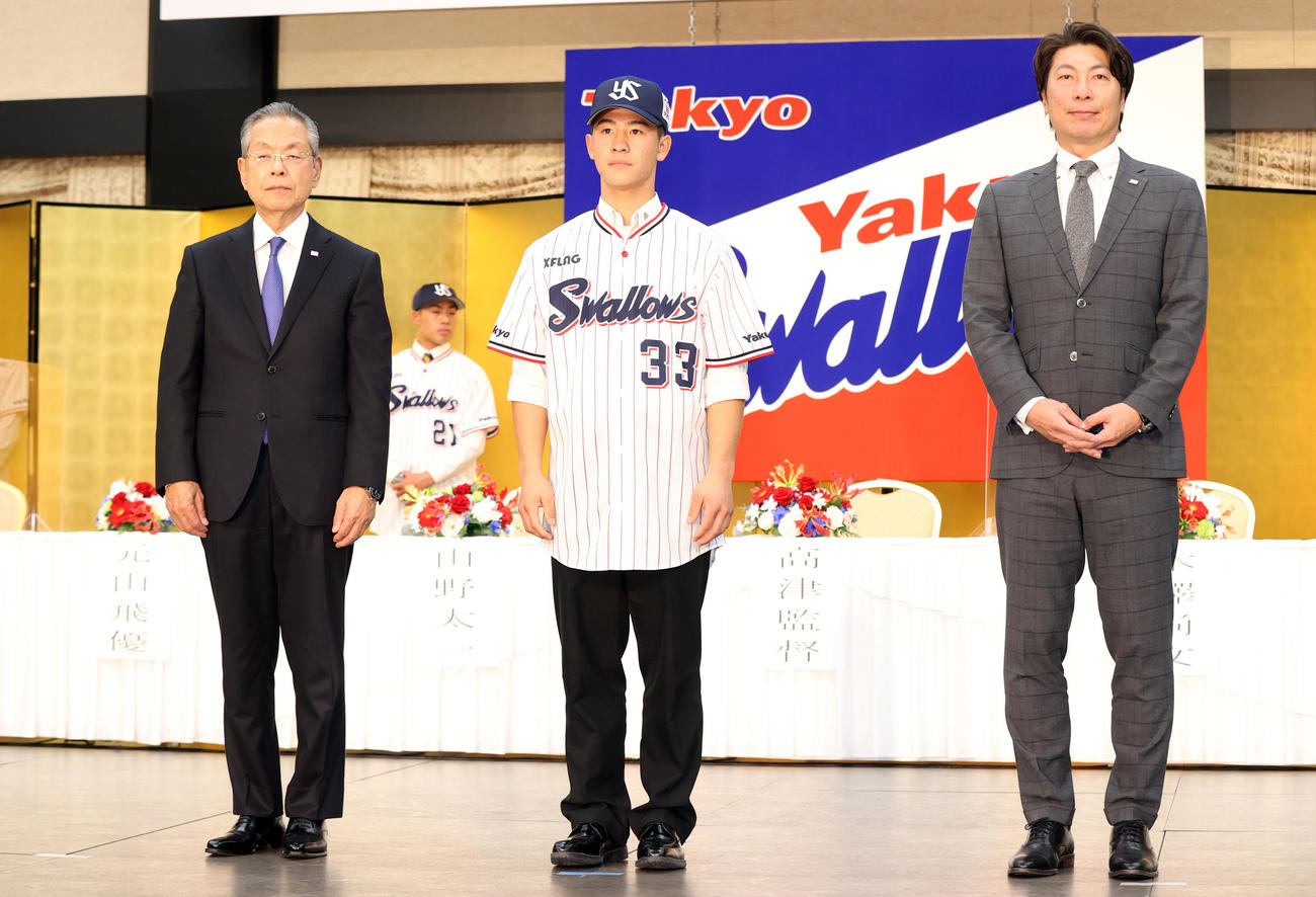 ヤクルト新入団発表会見で高津監督（右）からユニホームを着せてもらった後、記念撮影するドラフト3位の星稜・内山（中央）。左は衣笠球団社長（撮影・狩俣裕三）