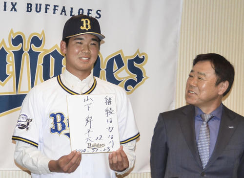 オリックスと仮契約を済ませた福岡大大濠・山下舜平大は、座右の銘を記した色紙を手に笑顔を見せる。右は福良GM（共同）