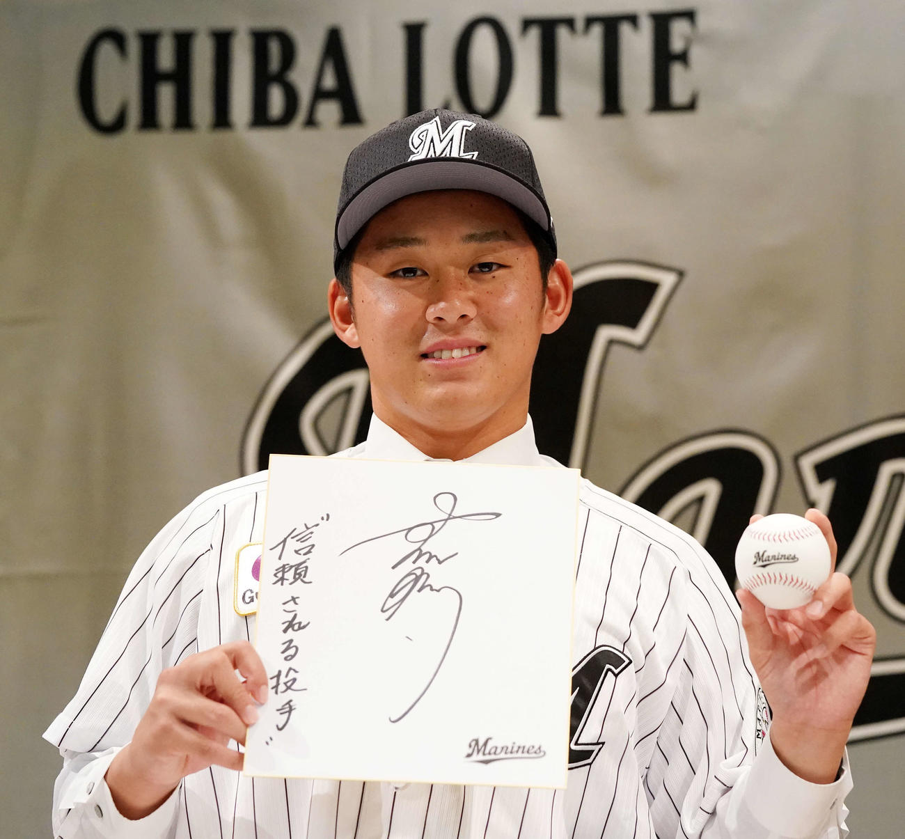 ロッテと仮契約を結んだドラフト1位の法大・鈴木は色紙にサインと「信頼される投手」と記した（撮影・江口和貴）