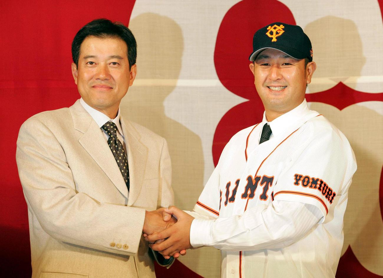 入団会見で原辰徳監督（左）とがっちり握手を交わす野口茂樹（05年11月17日撮影）