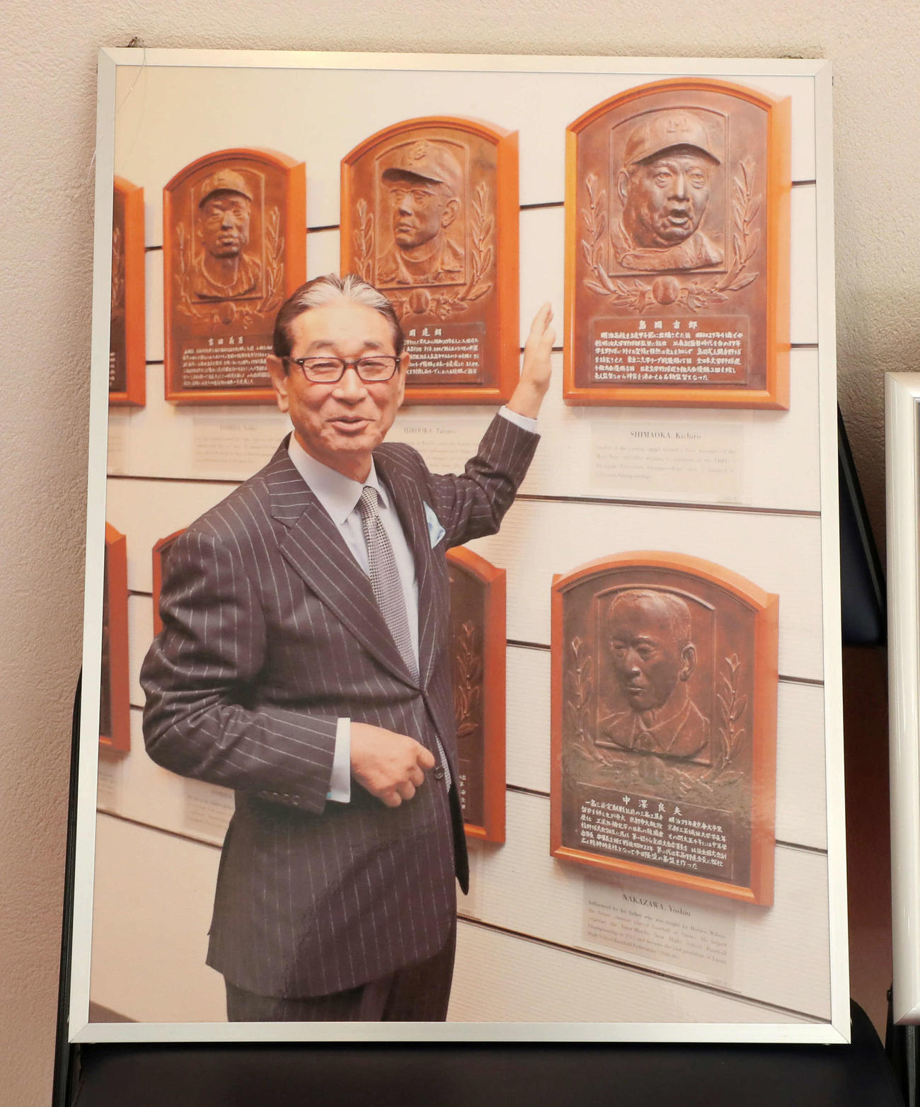 星野仙一氏が生前過ごしていた自室に飾られている、恩師で殿堂入りしている明大・島岡吉郎監督のレリーフの前で笑顔を見せる星野仙一氏の写真パネル（撮影・加藤哉）