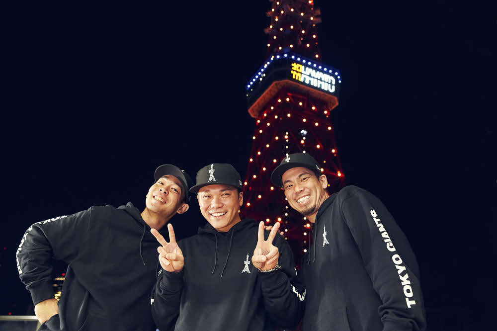 坂本勇人の通算2000安打を祝し、特別ライトアップされた東京タワーを背後に笑顔を見せる「88年会」の坂本（中央）と前田（右）、秋山（左）（球団提供）