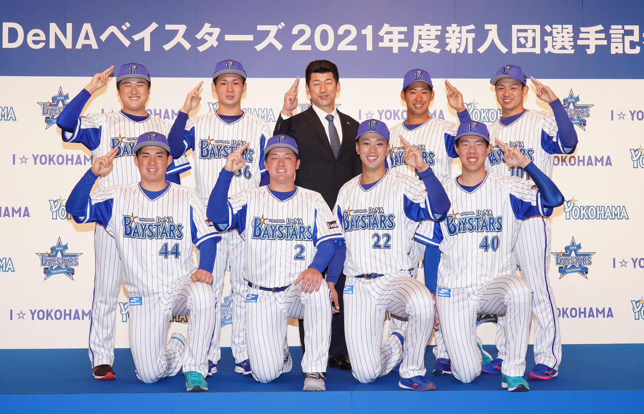 DeNA新入団会見で「ヨロシク」とポーズをとる三浦大輔新監督（後列中央）と新入団選手。前列左から4位の履正社高・小深田大地、2位の中大・牧秀悟、1位の明大・入江大生、3位の横浜高・松本隆之介、後列左から育成2位の横浜隼人高・加藤大、6位の静岡商高・高田琢登、5位のヤマハ・池谷蒼大、育成1位の法大・石川達也（代表撮影）