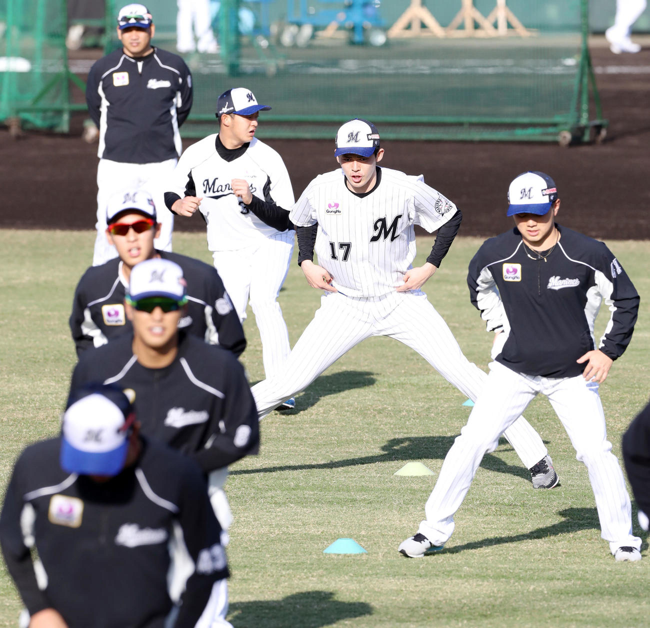 ロッテ沖縄・石垣島春季キャンプ　井口監督（左奥）が見つめる中ウオーミングアップするロッテ佐々木朗（中央）ら選手たち（2020年2月1日撮影）