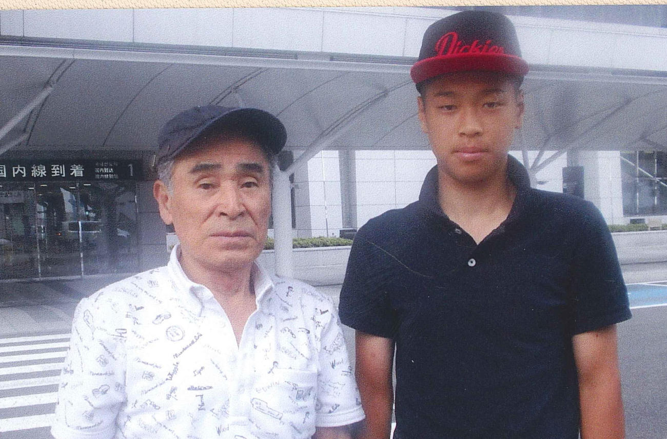仁川学院時代、祖父の勲さん（左）と空港で記念撮影する佐藤輝（佐藤勲さん提供）