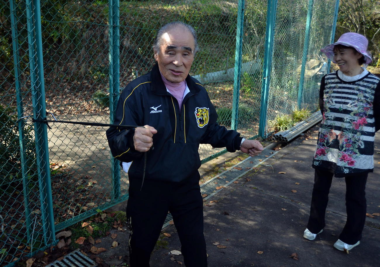 佐藤輝が体作りに利用したテニスコート横のゴムチューブを引っ張る祖父の勲さん。右は祖母の美智恵さん（佐藤勲さん提供）