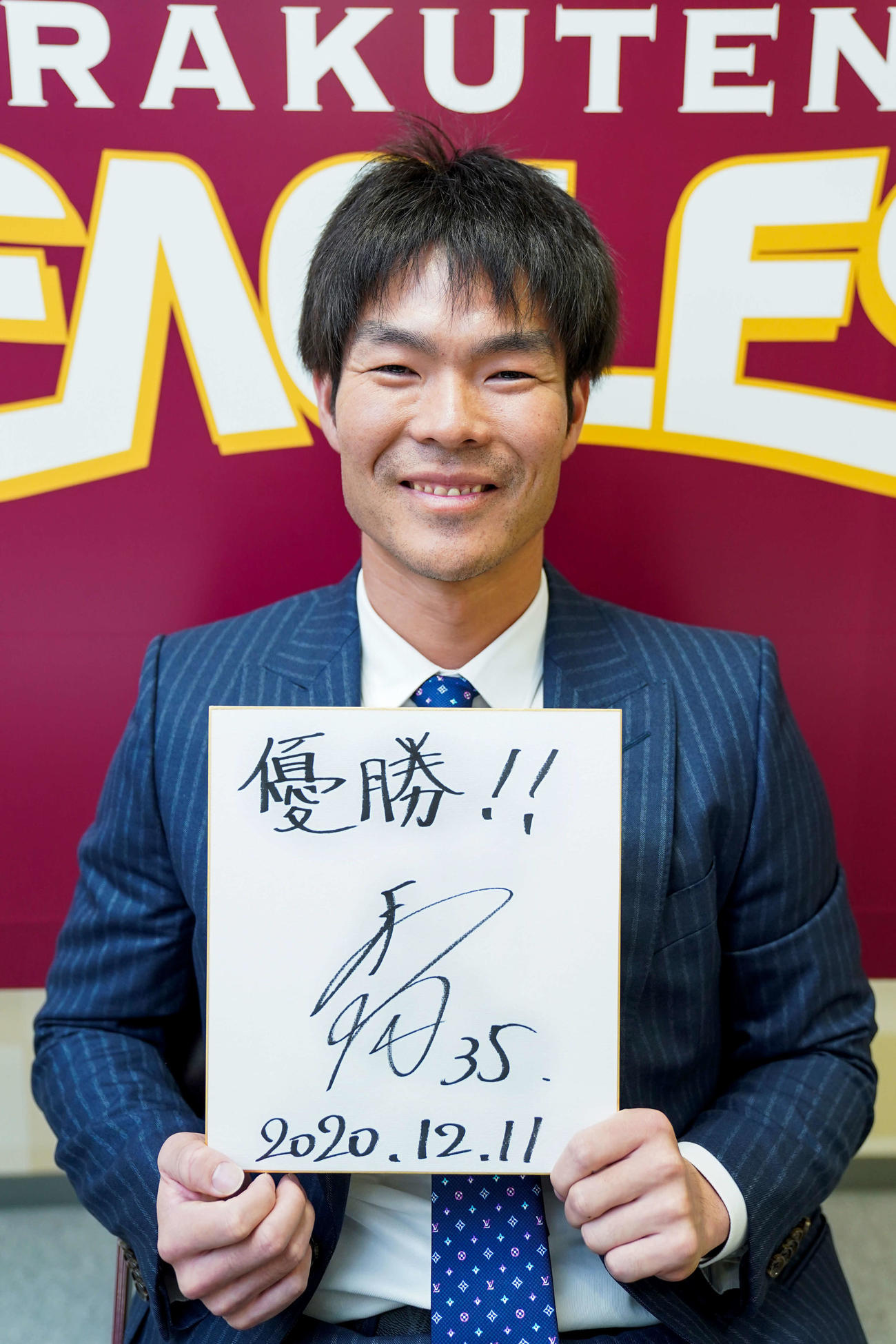 契約更改を終え、「優勝！！」と記した色紙を手に笑顔を見せる楽天島内（球団提供）