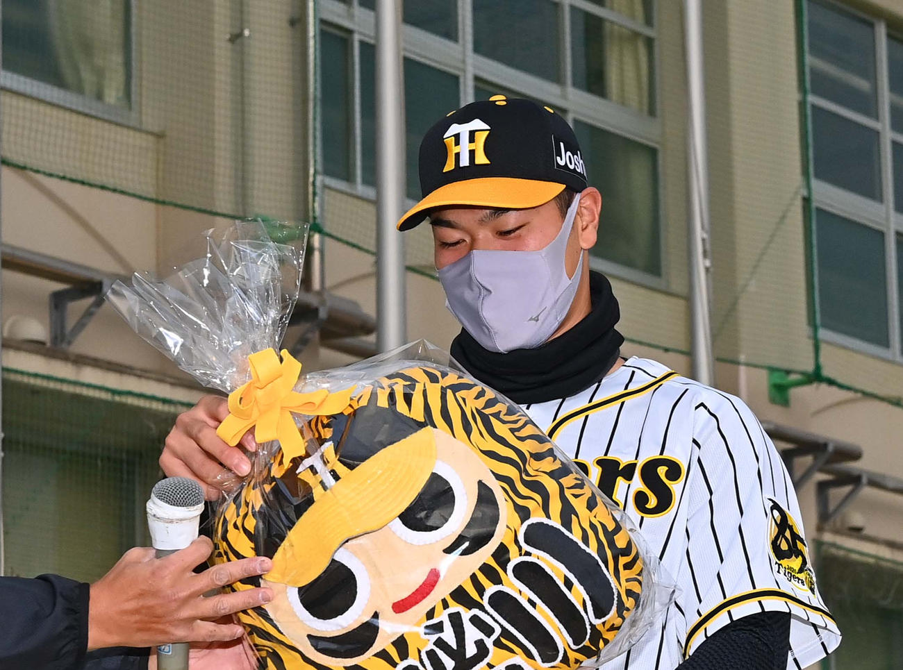 小学校時代に所属した甲東ブルーサンダースから贈られた必勝ダルマクッションを手に笑顔を見せる阪神佐藤輝（撮影・上田博志）