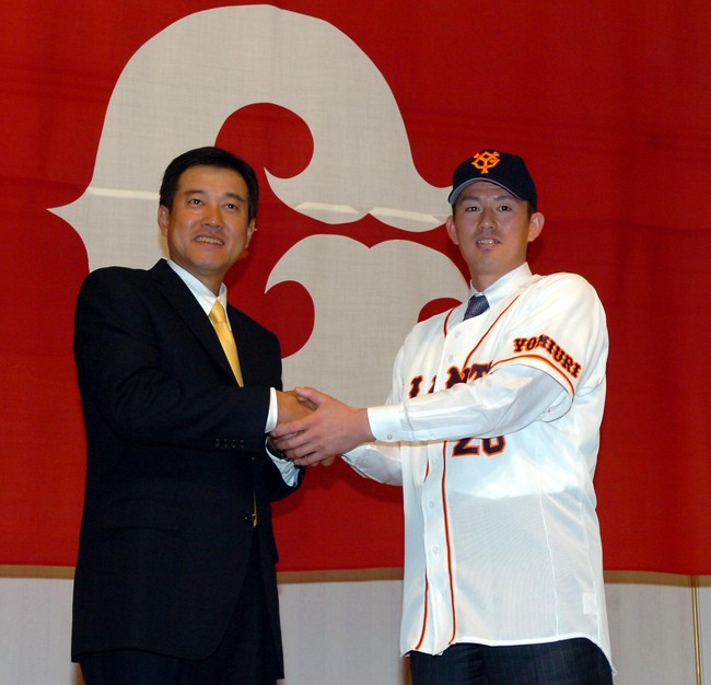 2005年11月27日、巨人への入団会見で、背番号20のユニホームを身にまとい笑顔で握手する豊田清（右）と原辰徳監督
