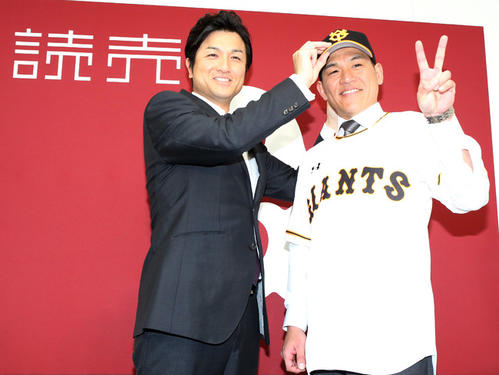 2015年12月7日、巨人入団会見で高橋由伸監督(左)から帽子をかぶせてもらい、うれしそうに笑う脇谷亮太