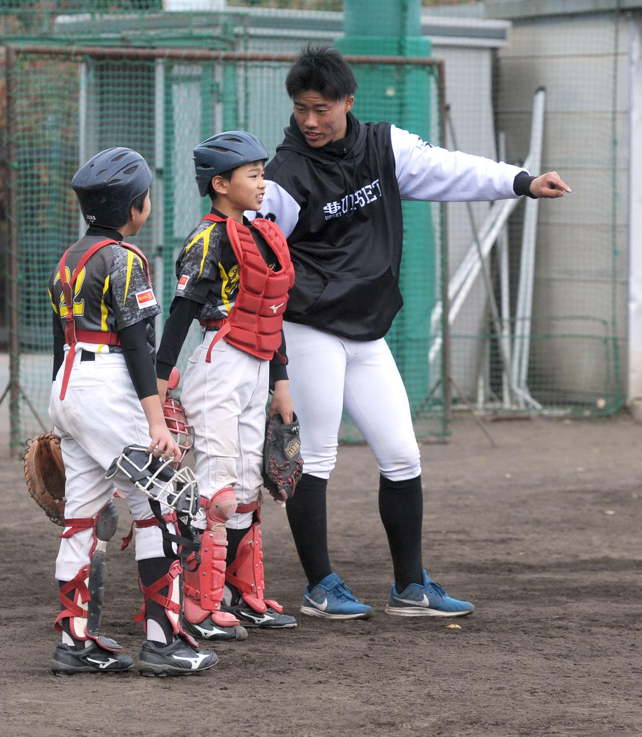 子どもにスローイングのアドバイスを送る磐田東高の二俣（右）