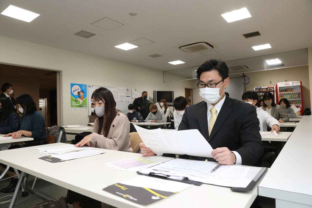 顔合わせで資料に目を通す野原監督（手前右）、半田（手前右から2人目）ら阪神タイガースWomenの選手たち（球団提供）