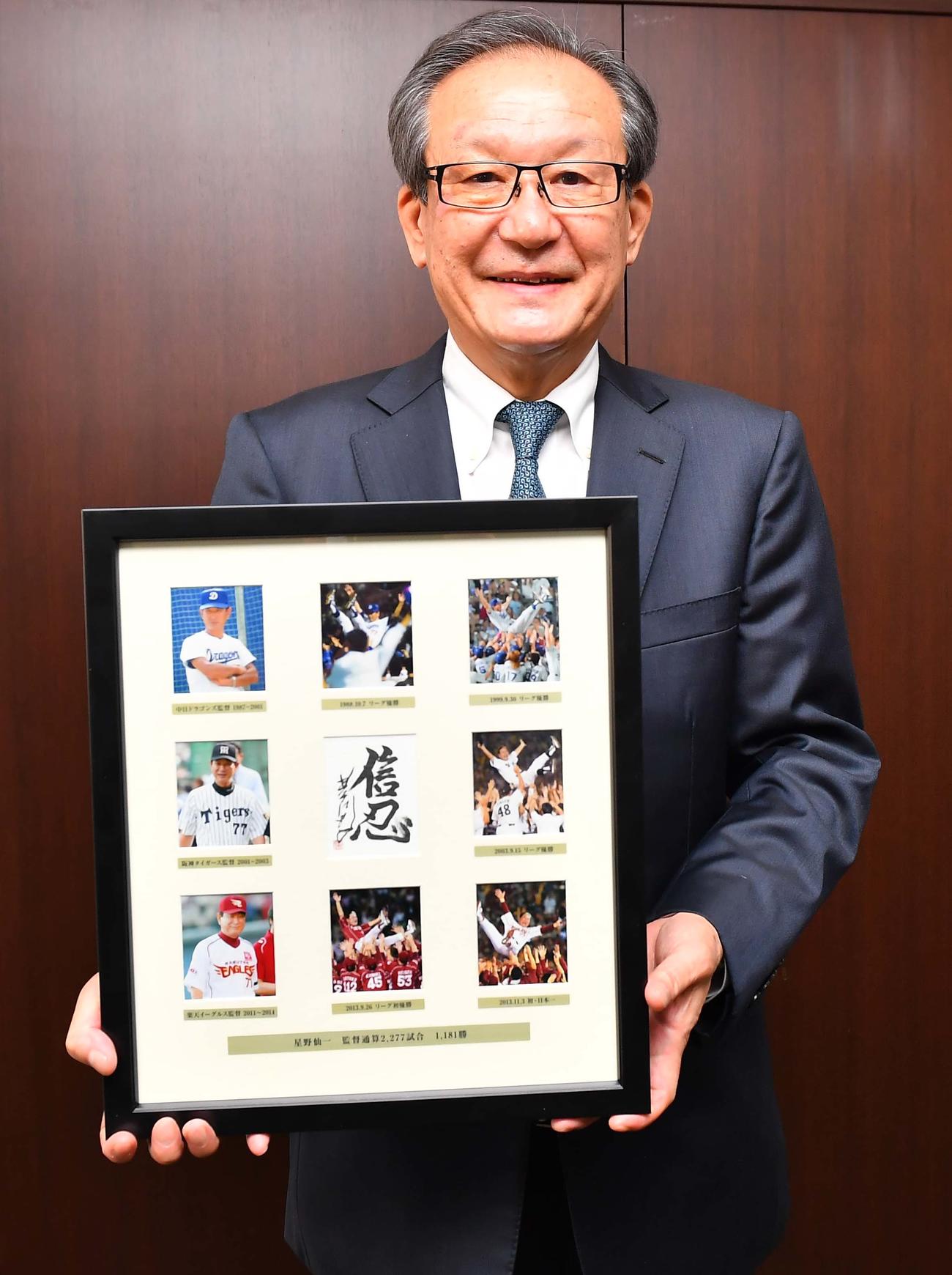 星野仙一さんの写真パネルを手に笑顔を見せるアシックス代表取締役会長CEOの尾山基氏（撮影・上田博志）