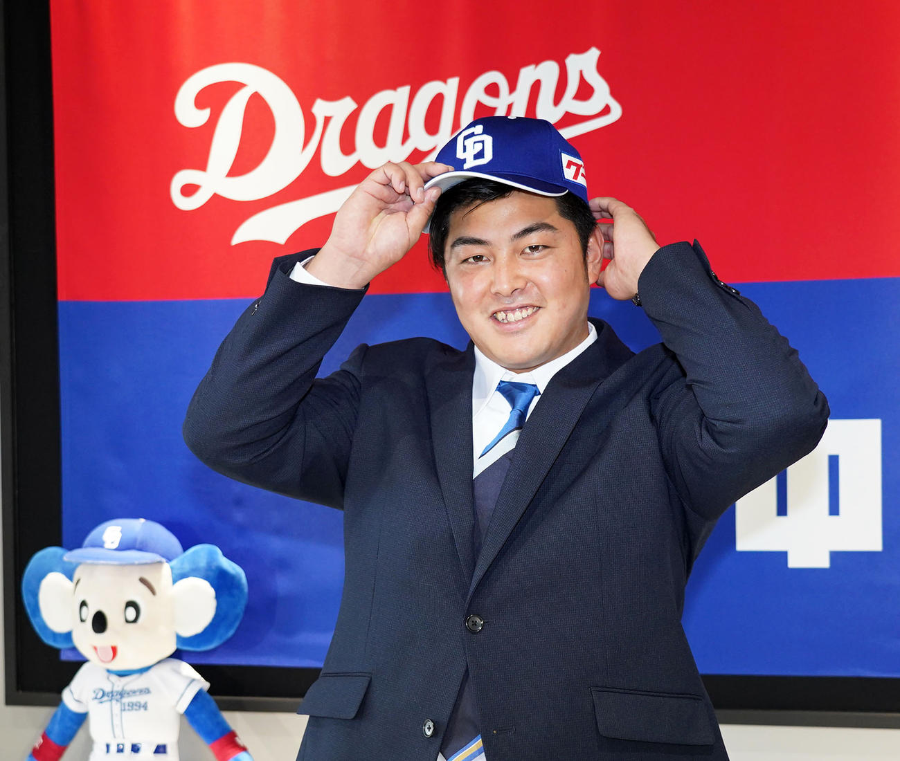 入団会見で中日の帽子をかぶり笑顔を見せる山下（撮影・森本幸一）