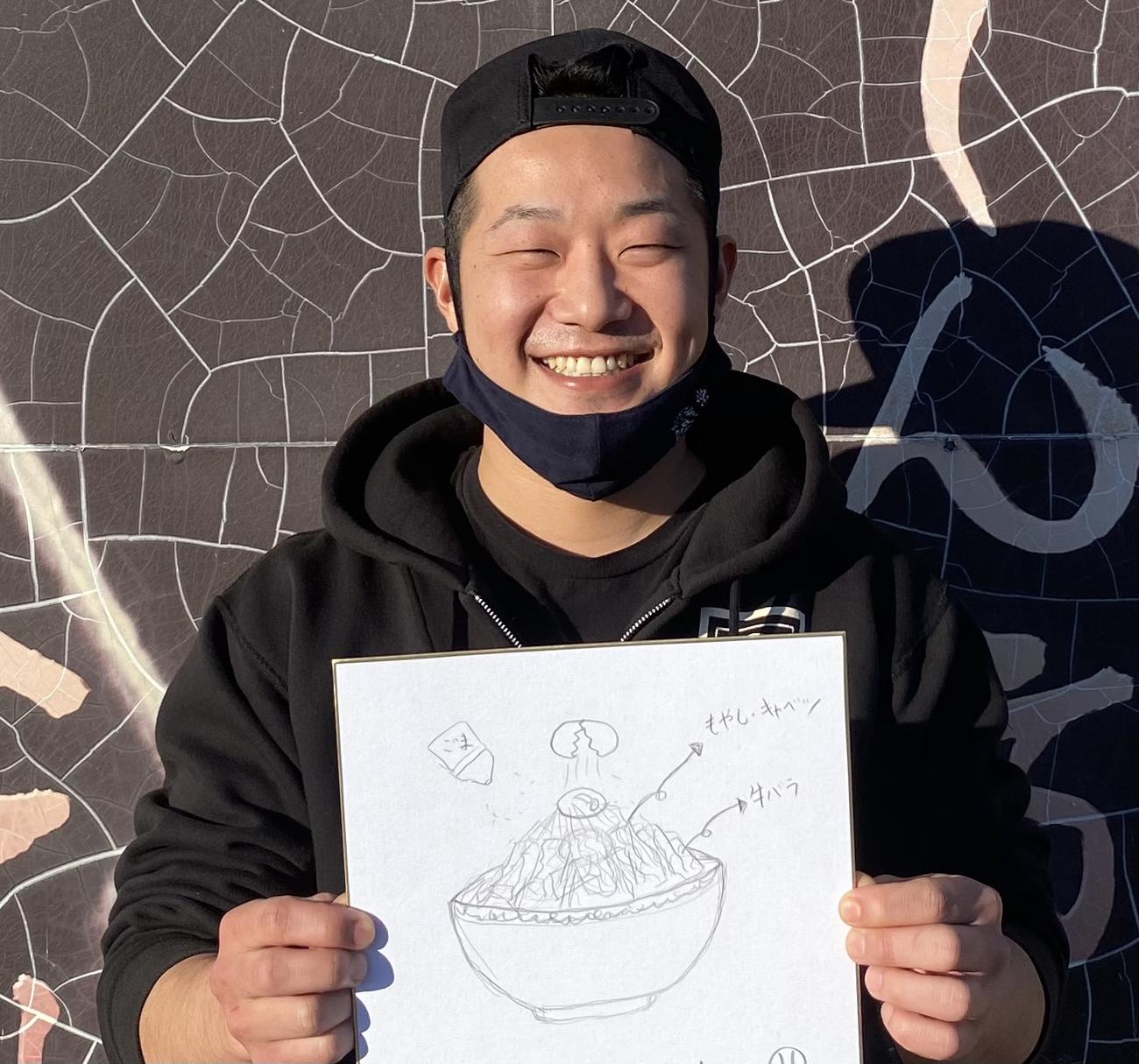 巨人松原の弟涼雄さんは、考案した「絆ラーメン」のイラストを手に笑顔を見せる（涼雄さん提供）