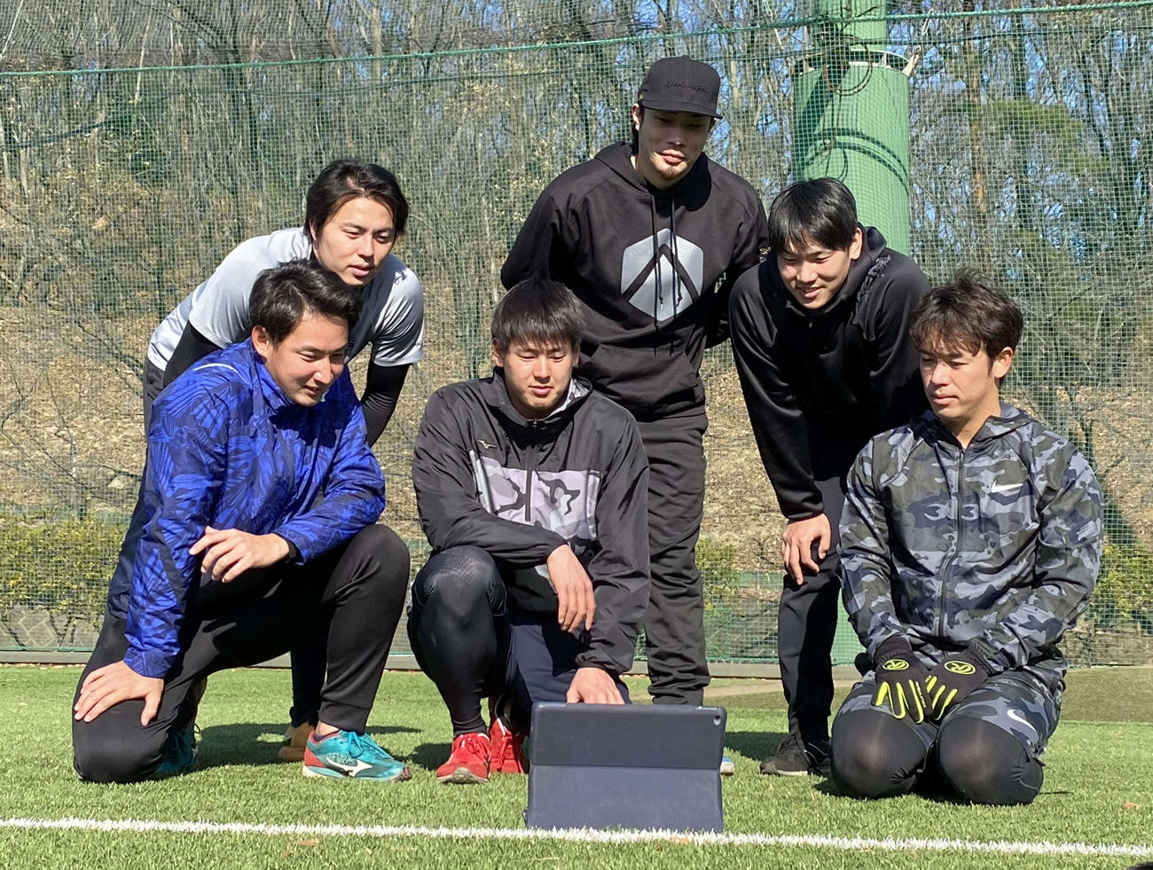 合同自主トレーニングの合間に箱根駅伝での創価大の力走を見守るOB選手たち。前列右からヤクルト小川、ヤクルト杉山、日本ハム望月、後列右からソフトバンク石川、DeNA倉本、ソフトバンク田中（撮影・湯本勝大）