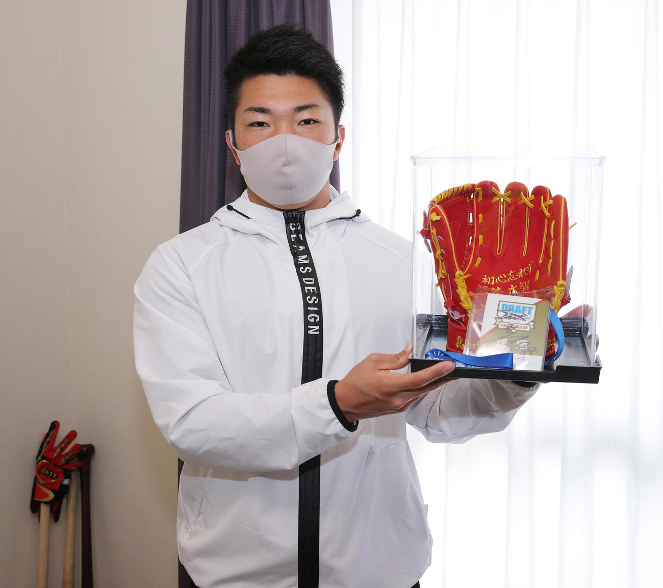 プロ入り記念で作ってもらったディスプレー用グラブと矢野監督のサイン入りドラフト会議の通行証を入寮で持参した石井大（球団提供）
