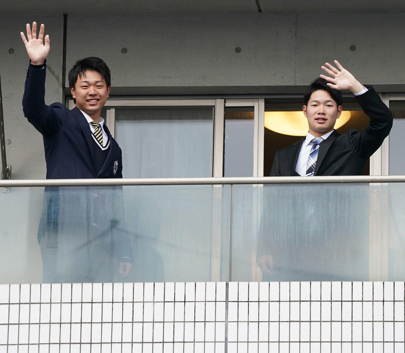 昇竜館に入寮しテラスから手を振る中日高橋宏（左）と森（撮影・森本幸一）
