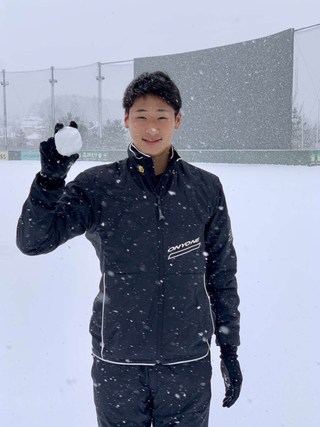 グラウンドに積もった雪をボールに見立て、笑顔を見せる楽天ドラフト6位の内（球団提供）