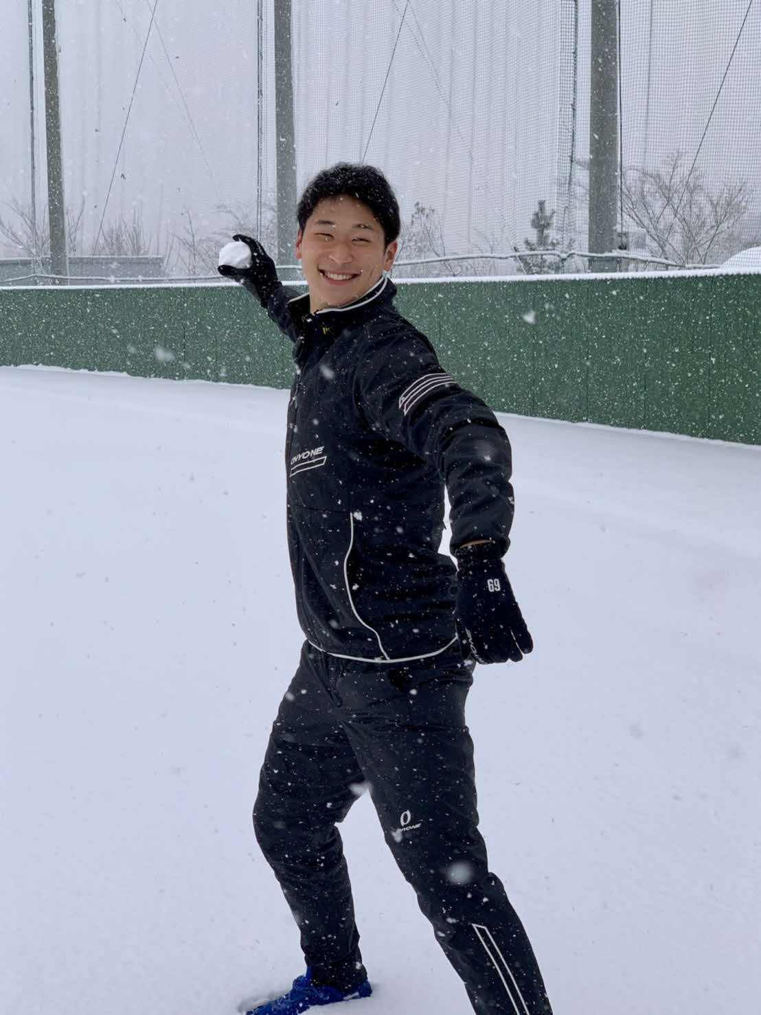 グラウンドに積もった雪をボールに見立て、笑顔で投げようとする楽天ドラフト6位の内（球団提供）
