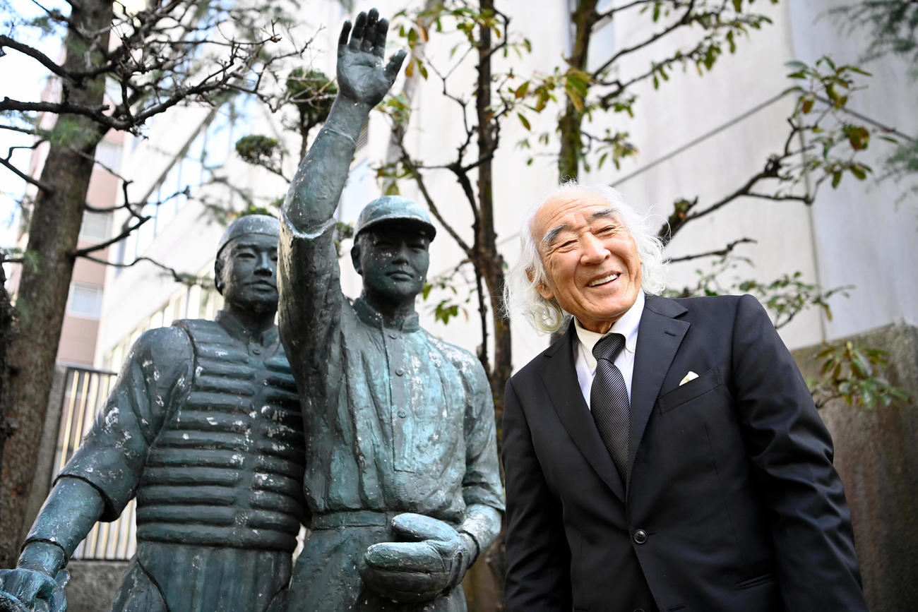 野球殿堂入りし、日本高野連の庭にある銅像の前で笑顔を見せる佐山和夫さん（代表撮影）