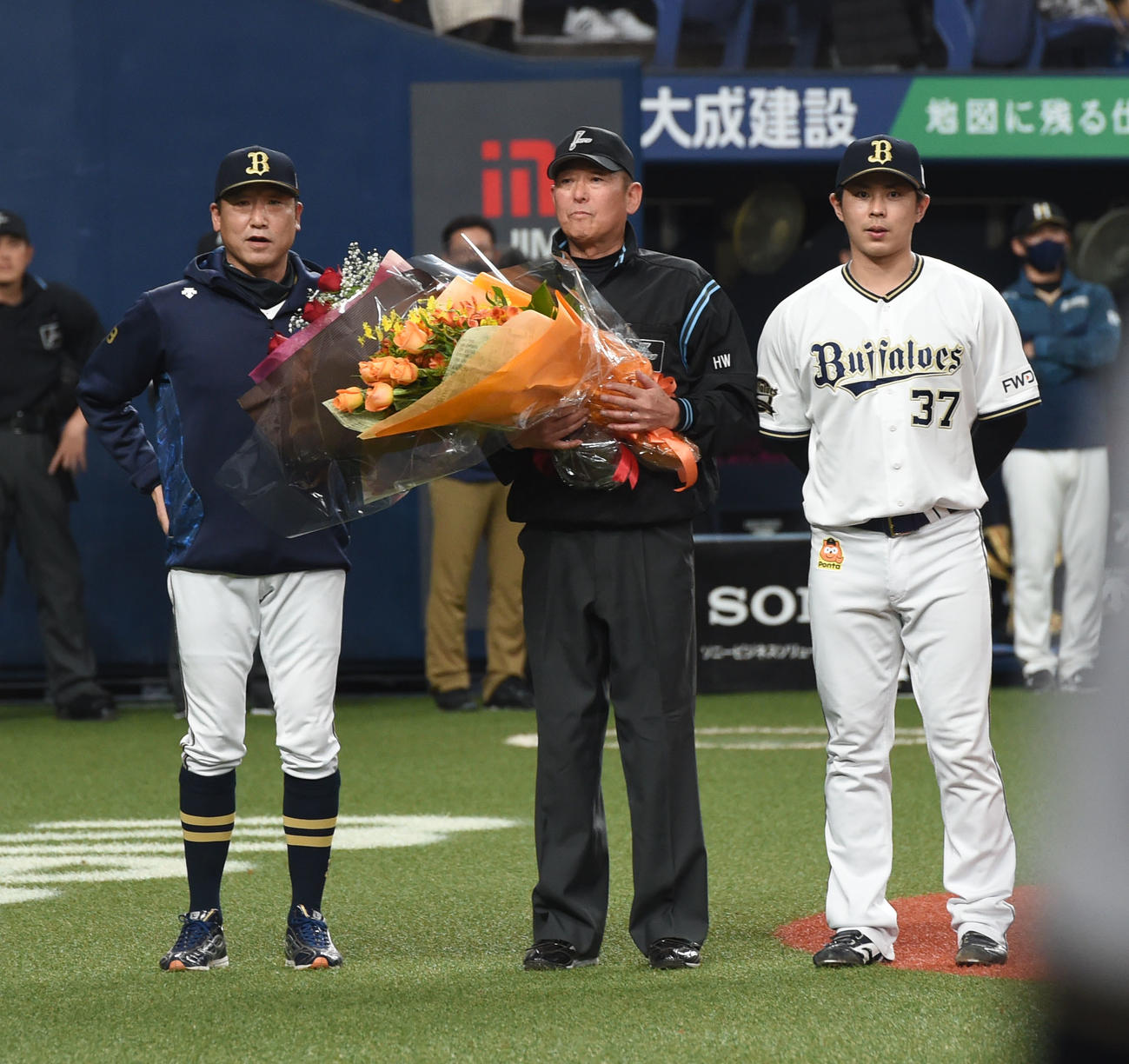 20年11月、引退となり中嶋監督代行（左）と若月（右）から花束を贈られた佐藤純一審判員