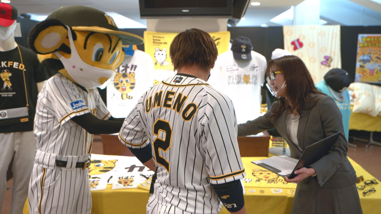 背番号2を背負い、新作タイガースグッズ内覧会で説明を受ける梅野（球団提供）
