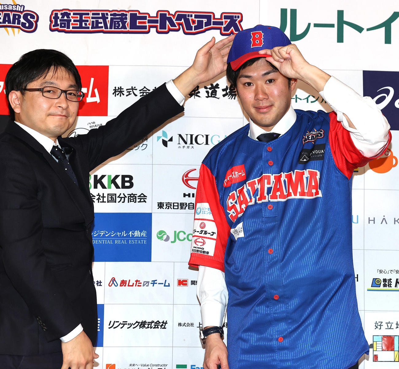 BC・埼玉の入団会見で、ユニホームを着て、山崎CEO（左）から帽子をかぶせてもらう由規（撮影・浅見桂子）