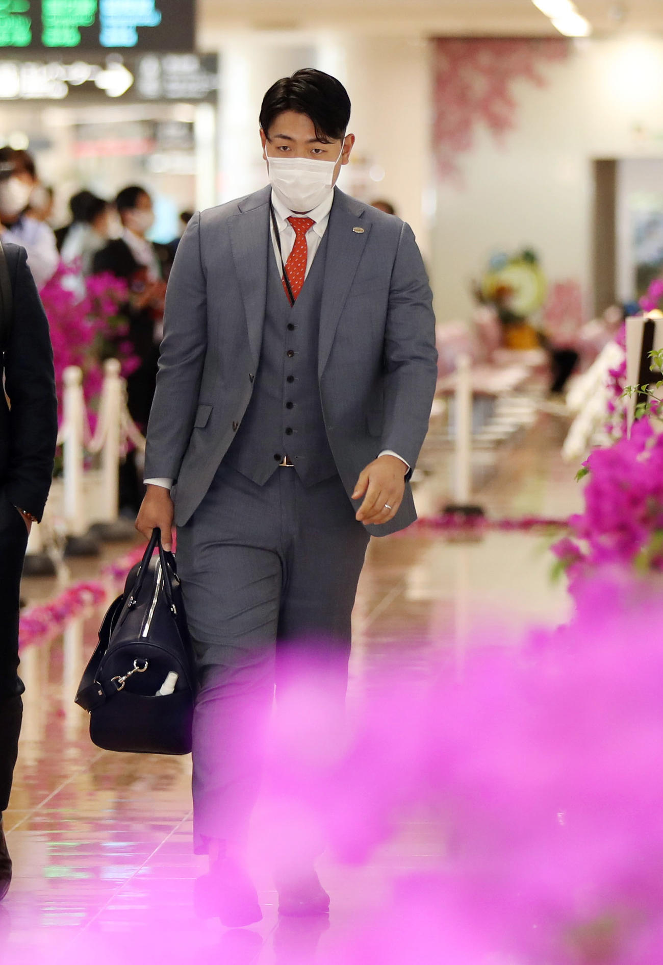 宮崎空港に到着し、ブーゲンビリアの花道を通る岡本和（撮影・狩俣裕三）