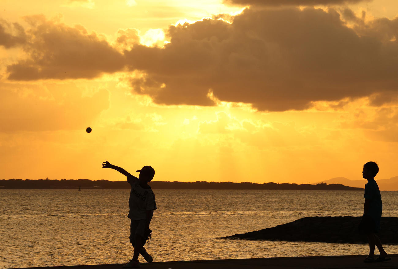 海沿いの公園で日没直前の夕日を浴びながらキャッチボールを楽しむ野球少年たち（撮影・垰建太）