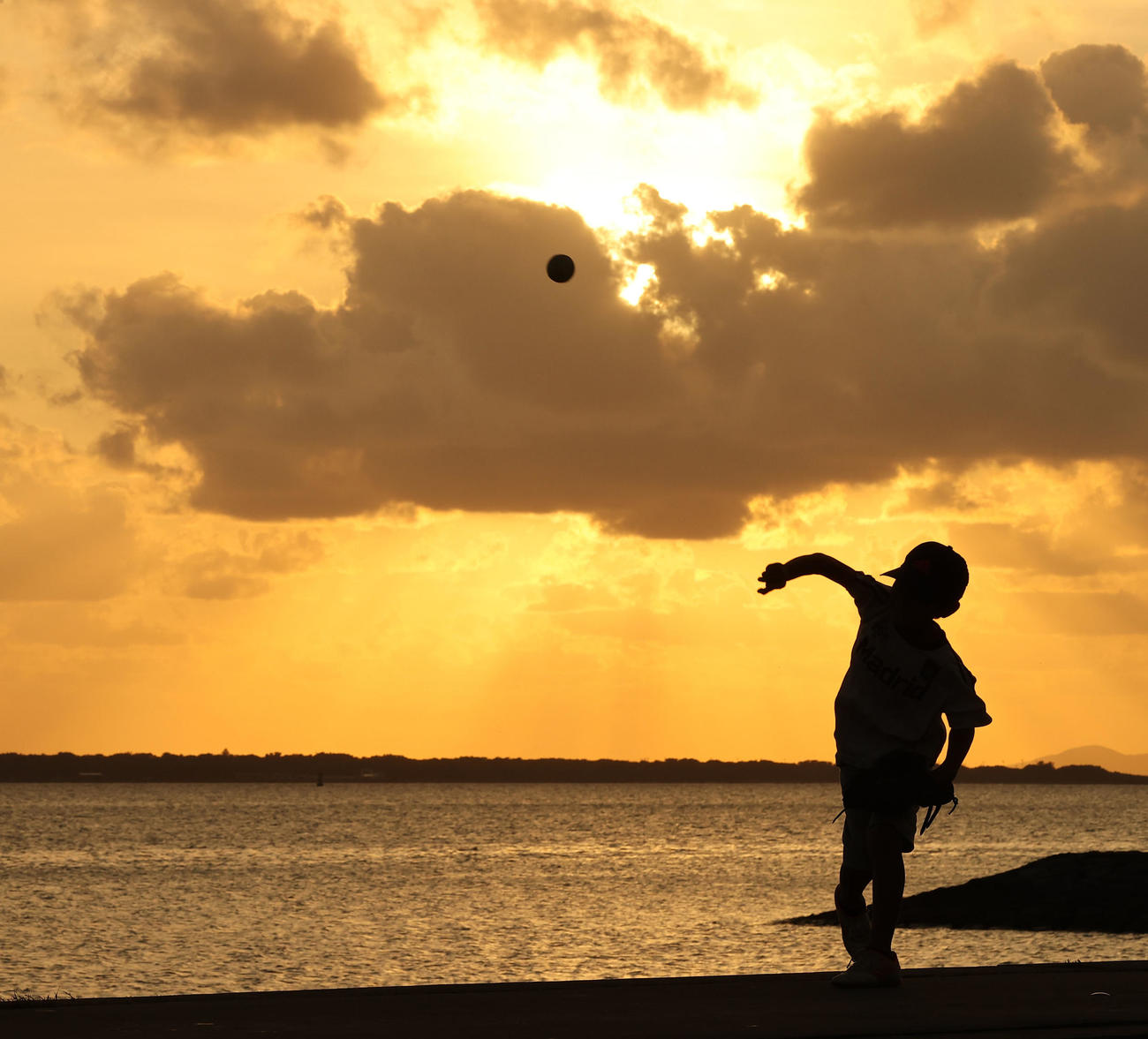 海沿いの公園で日没直前の夕日を浴びながらキャッチボールを楽しむ野球少年（撮影・垰建太）
