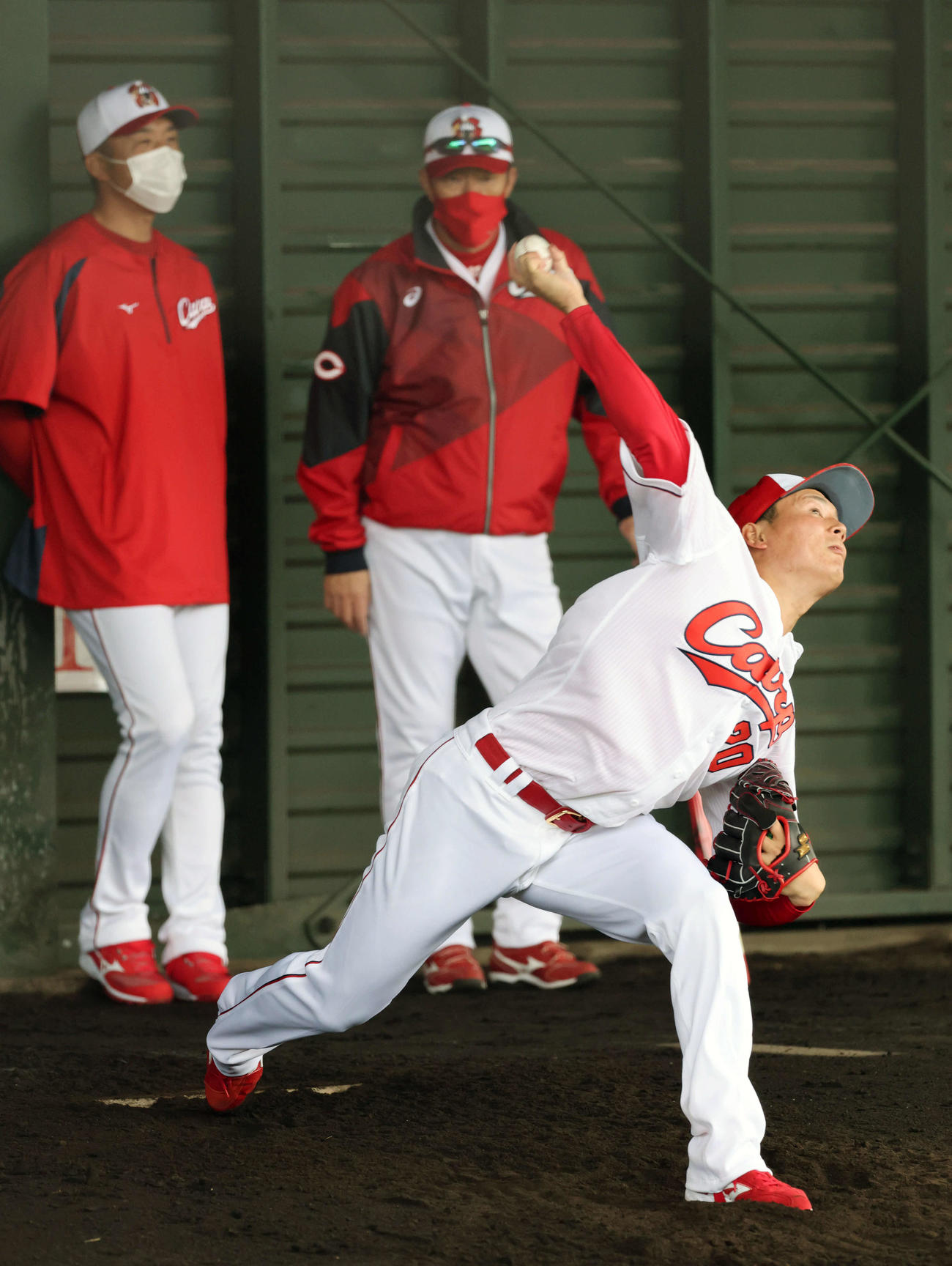 ブルペンで投げる栗林。後方左から、永川投手コーチ、佐々岡監督（撮影・加藤孝規）