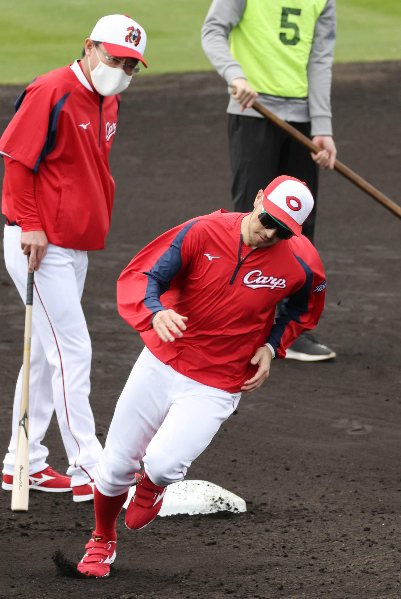 プロ野球広島沖縄キャンプ　ベースランニングをする菊池涼。左は河田ヘッドコーチ（撮影・加藤孝規）