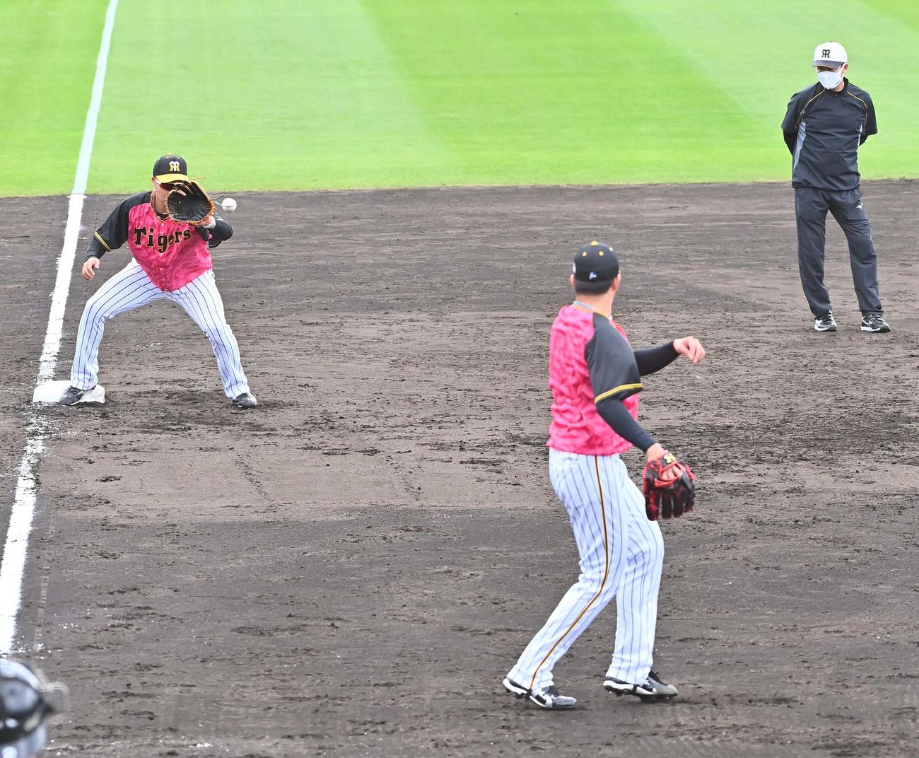 投内連係プレーの練習で三塁へ送球する岩貞祐太を見る川相昌弘臨時コーチ（右）（撮影・上田博志）
