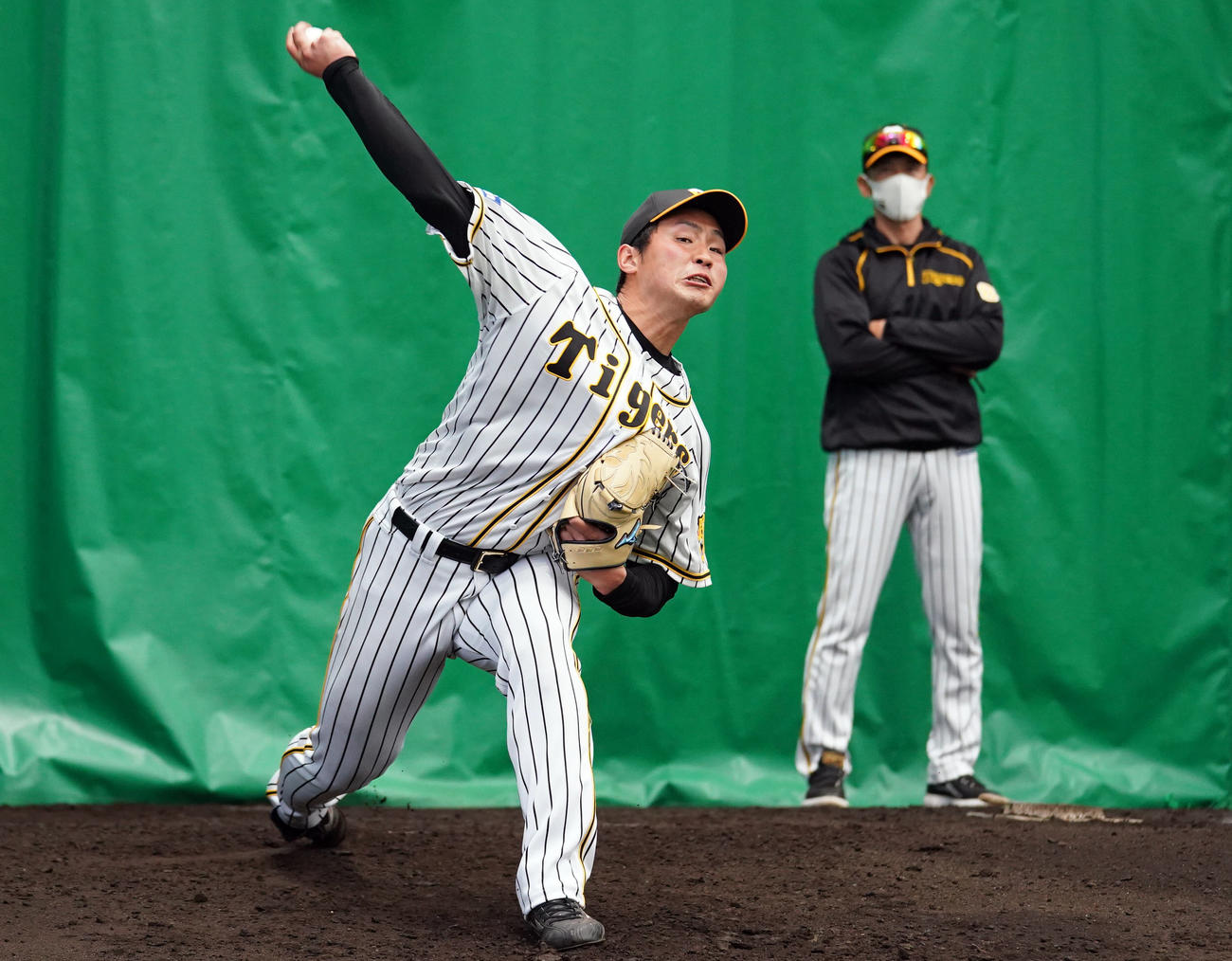 ブルペンで投球する阪神佐藤蓮。後方は見つめる矢野監督（代表撮影）