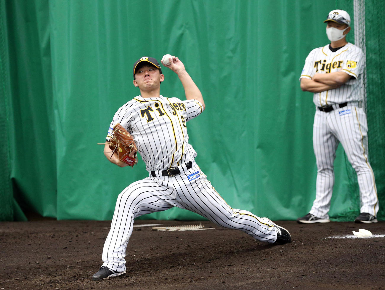 ブルペンで投球する阪神伊藤将。右は福原コーチ