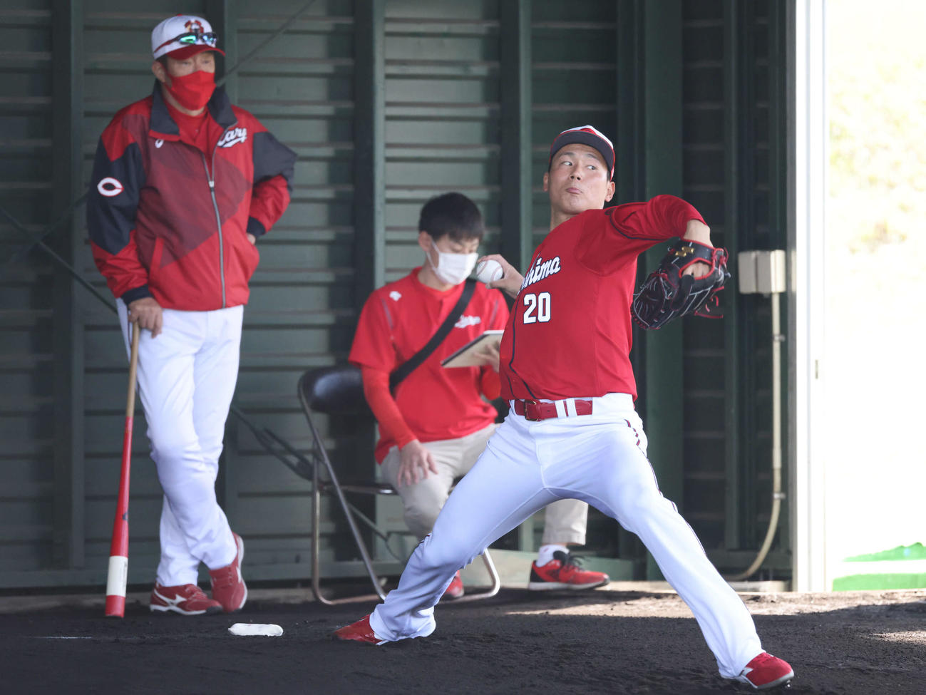 プロ野球広島沖縄キャンプ　ブルペンで投げるドラフト1位の栗林。左は佐々岡監督（撮影・加藤孝規）
